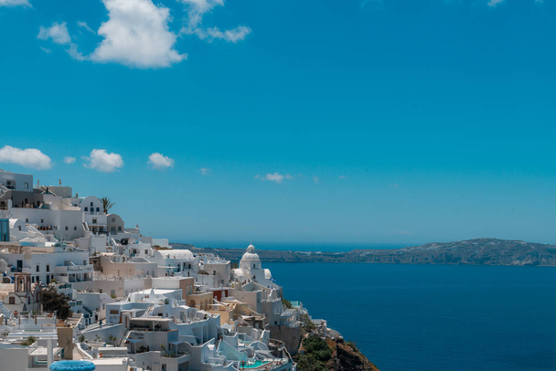 Santorini, Greece. Picturesque view of traditional cycladic Santorini houses on small street with flowers in foreground. Location: Oia village, Santorini, Greece. Vacations background. - Foto, Imagen
