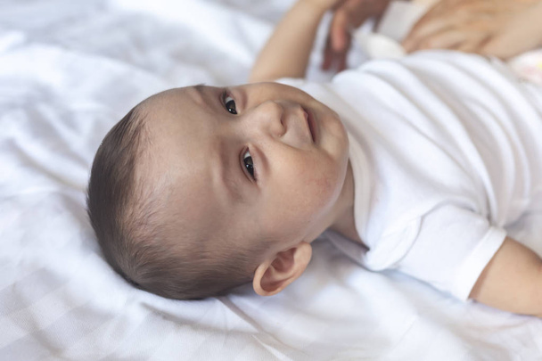 Vihainen 6 kuukauden ikäinen vauva sängyssä. Pikkupoika tuntee olonsa epämukavaksi ja onnettomaksi. Surullinen poika katselee kameraa. Kopioi tila
 - Valokuva, kuva