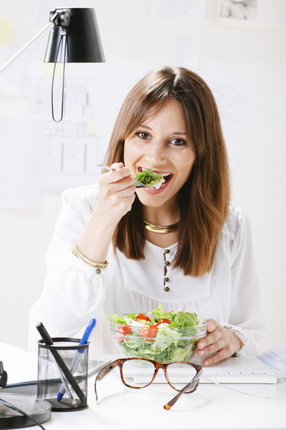 Young woman creative designer eating a salad in office. - Valokuva, kuva