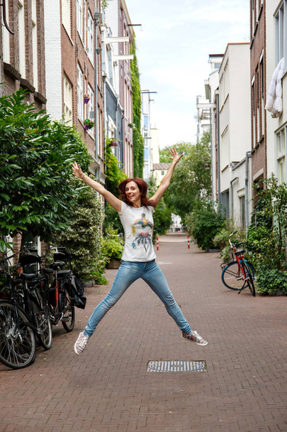Mädchen jubelt beim springen in der engen straße von amsterdam - Foto, Bild