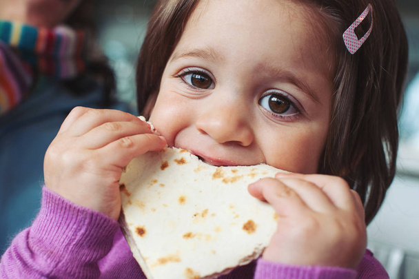 Young girl eating bread. - Φωτογραφία, εικόνα