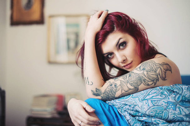 Sensual portrait of beautiful girl with tattoo lying on bed.  - Фото, зображення