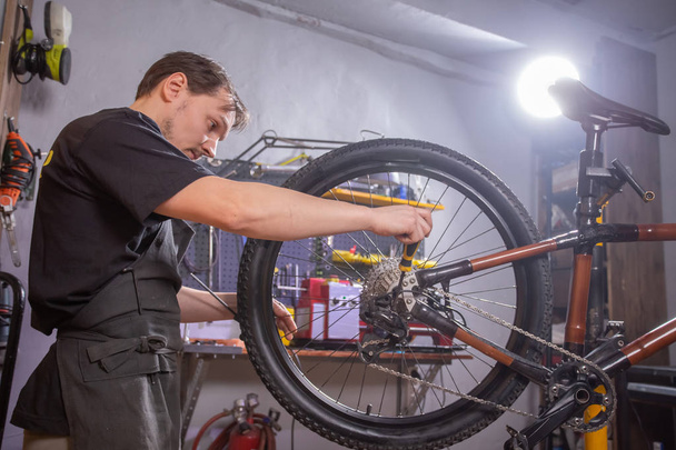 Conceito de serviço, reparo, bicicleta e pessoas - Reparação mecânica de uma bicicleta de montanha em uma oficina
 - Foto, Imagem