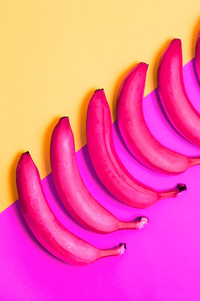 Close - up of pink bananas on blue and yellow background, top view - Photo, image