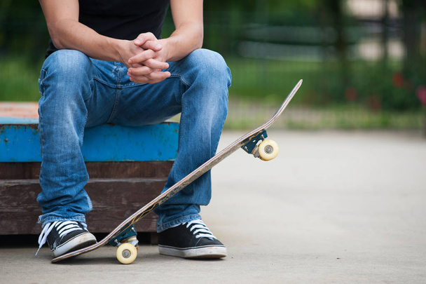 cropped shot of Man sit with skateboard. - Zdjęcie, obraz