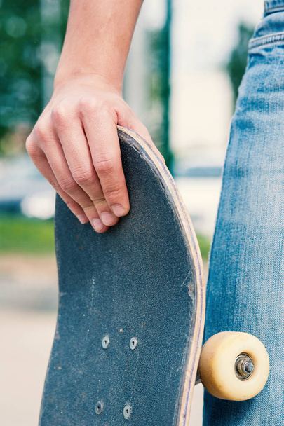 Detail of man hand holding skateboard at skatepark. - Foto, immagini