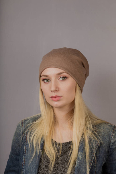 Porträt eines schönen jungen Mädchens in einem stilvollen Kopfschmuck mit natürlichem Make-up auf grauem Hintergrund. - Foto, Bild