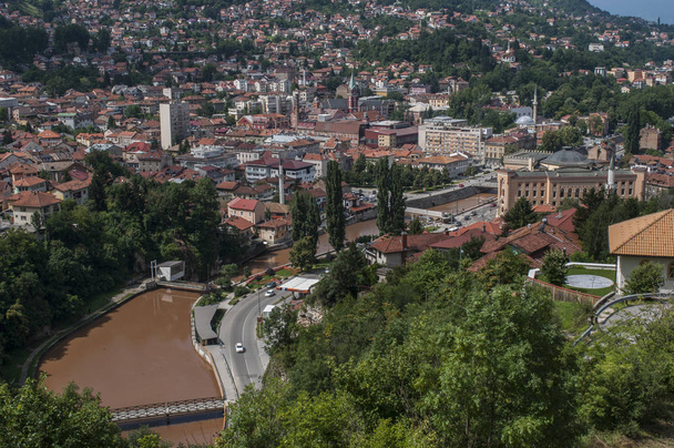 Bosnien und Herzegowina, 07 / 08 / 2018: Luftaufnahme der Skyline der Hauptstadt Sarajevo, umgeben von den Dinarischen Alpen und am Fluss Miljacka gelegen, von zuta tabija (gelbe Festung) aus gesehen)  - Foto, Bild