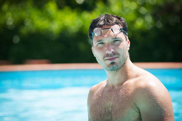 Portrait of a handsome man with goggles in swimming pool.  - Valokuva, kuva