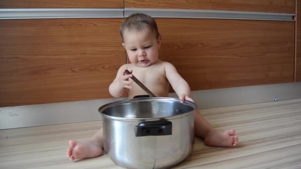 cute zes maanden oude baby jongen spelen met koken pot en houten lepel - Video