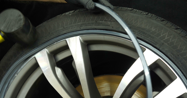 Profesionální měnič pneumatik mění ochranu automobilù (pneumatik) pomocí různých nástrojů. Pracovník v automobilové službě vznáší (snižuje) auto na zdířky. Koncepce: Automatická myčka aut, garáže, nástroje, údržba. - Záběry, video