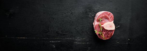 Raw fresh cross cut veal shank for making Osso Buco with spices and herbs on a black background. Top view. Free space for your text. - Foto, immagini