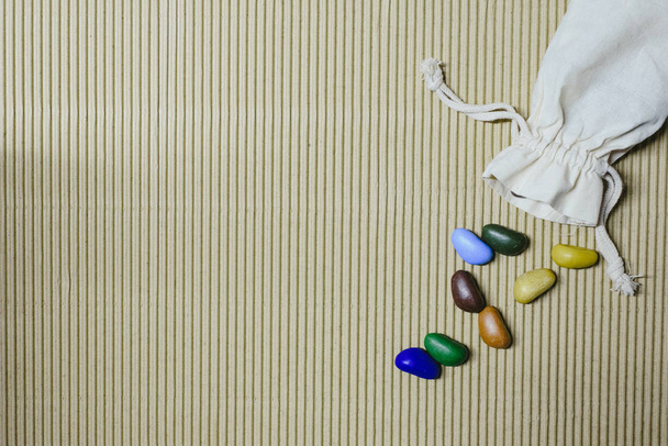 Hintergrund aus farbigen Kunststeinen auf welligem Papier verstreut mit - Foto, Bild