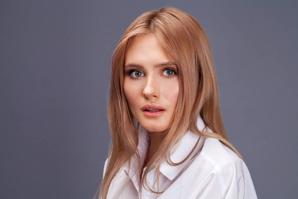 Closeup portrait of a young beautiful blonde woman in a white sh - Фото, изображение