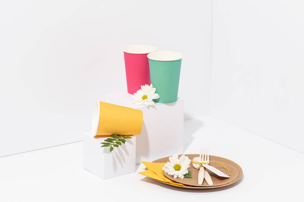 Recyclable multicolored paper tableware, cornstarch cutlery over white - 写真・画像