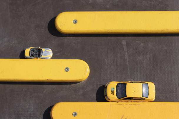 青い背景に黄色の木製の棒に黄色の車。駐車場、車の配置。子供時代、ゲームと時間の推移、大人と子供のゲーム、車の概念. - 写真・画像