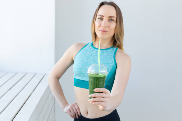 Healthy, sport, diet and people concept - Successful fitness urban woman recommending detox smoothie - Photo, Image