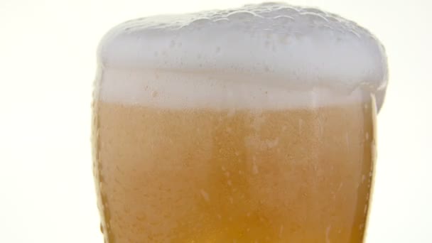 Κοντινό πλάνο ρίχνει μπύρα lager σε ποτήρι πάνω από λευκό - Πλάνα, βίντεο