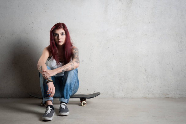 Woman with skateboard portrait against concrete wall. - Foto, imagen