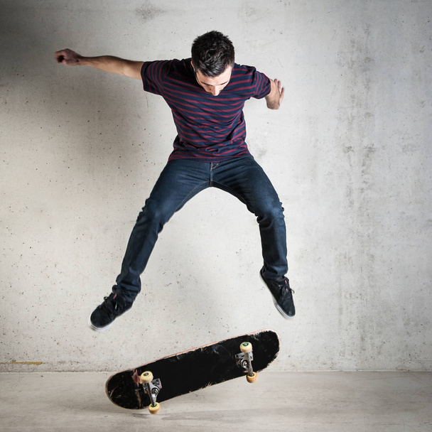 Skateboarder jumping against concrete wall. - Zdjęcie, obraz