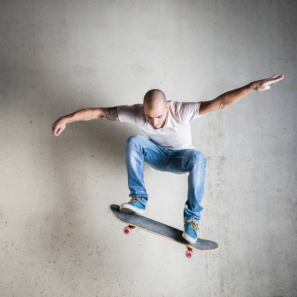 Skateboarder jumping against concrete wall.  - Photo, image