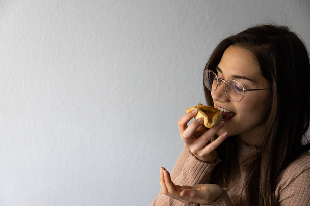 Beautiful and happy women portrait eating hamantash Purim apricot cookie - Photo, Image