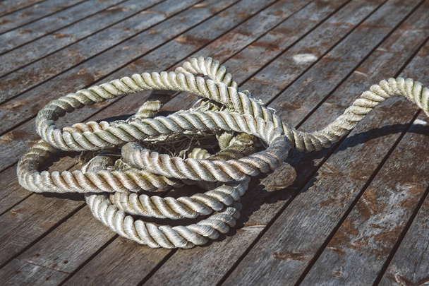 Gros plan d'une épaisse corde d'amarrage usée sur une jetée en bois. Peut être utilisé comme bannière
 - Photo, image