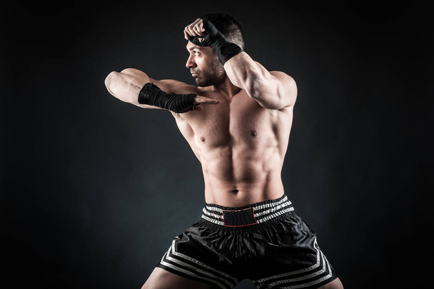 Sportsman kick boxer fighting against black background.  - Foto, Imagem