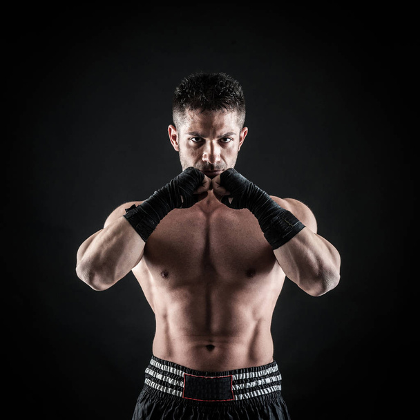 Sportsman kick boxer intense portrait against black background.  - Foto, afbeelding