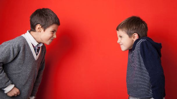 Young brothers arguing against red background. - Zdjęcie, obraz