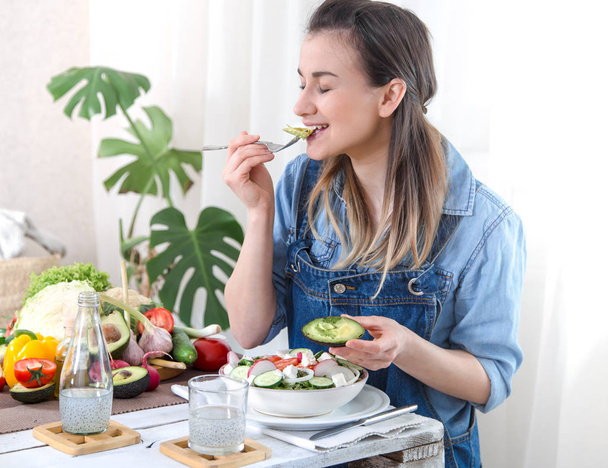 Молода і щаслива жінка їсть салат за столом
 - Фото, зображення