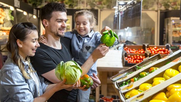 Une famille heureuse achète des légumes. Famille joyeuse de trois personnes au choix
  - Photo, image