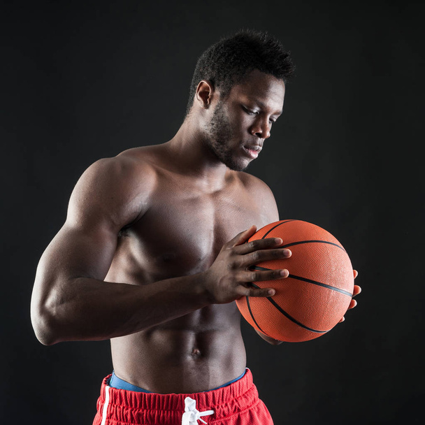 Confident young black man shirtless with basket ball against bla - Photo, image