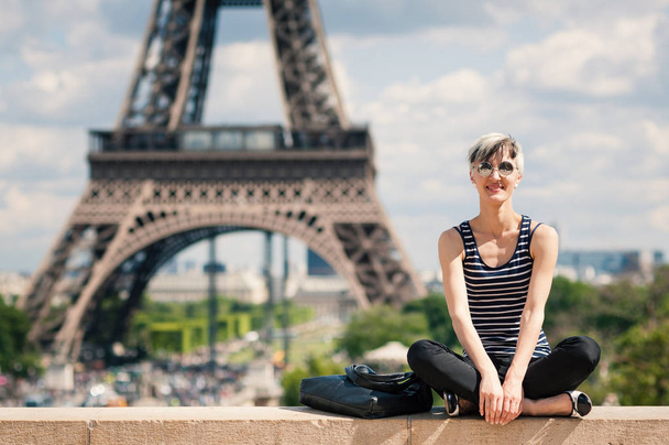 Smiling young blonde woman portrait in front of the Eiffel Tower in Paris, France. Filtered image. - Foto, Imagen