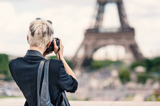 Young woman with camera taking a photo in front of the Eiffel Tower. Paris, France.  - Foto, Imagen