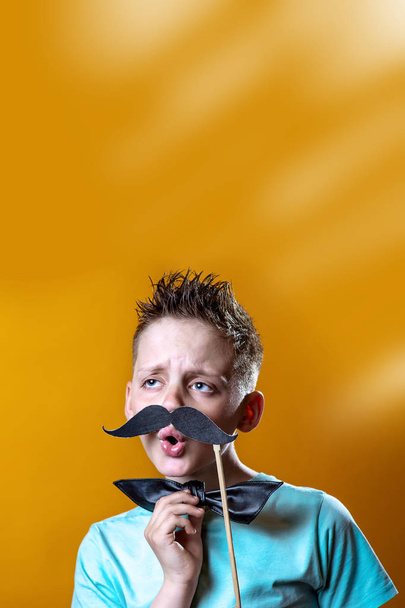boy in a light t-shirt with a mustache and a bow sings and says funny - Foto, Bild
