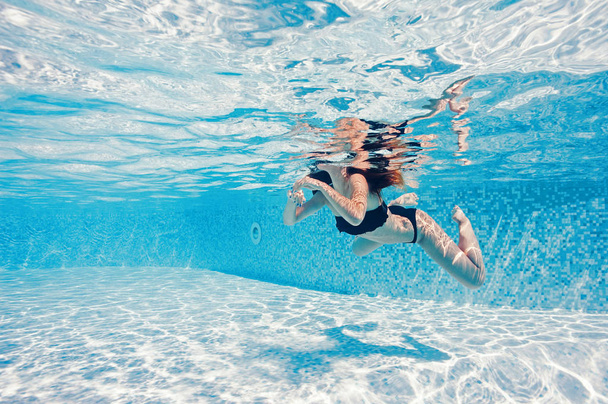 Underwater shot of woman wearing black bikini swimming in pool.  - Photo, image