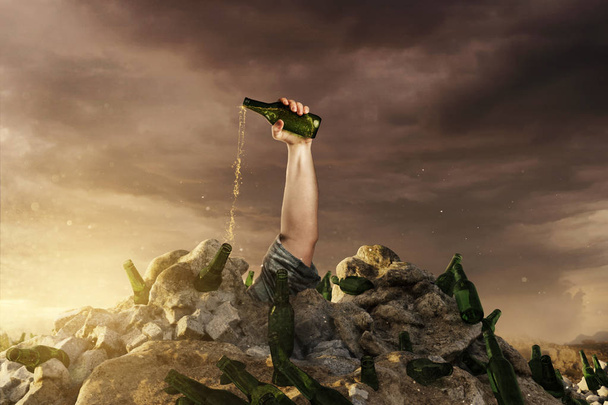 hand with green beer bottle raising up from rubbish dump and emp - Foto, imagen