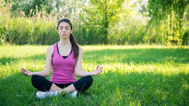 Retrato de mulher jovem praticando ioga ao ar livre em um parque
. - Foto, Imagem