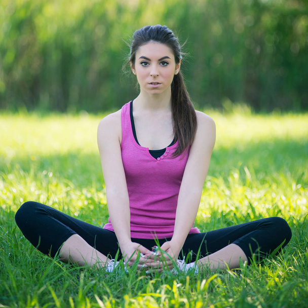 Retrato de mujer joven practicando yoga al aire libre en un parque
. - Foto, imagen