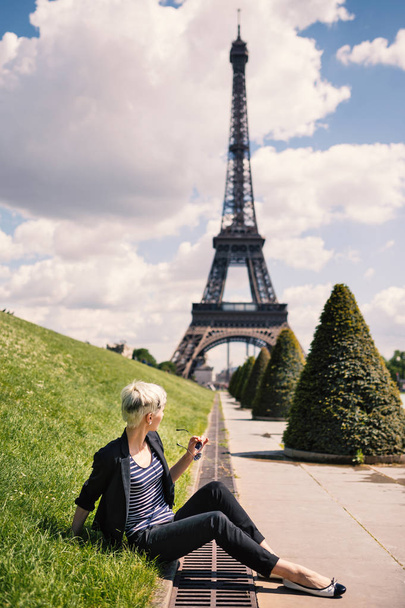 Young blonde woman portrait in front of the Eiffel Tower in Paris, France.  - Φωτογραφία, εικόνα