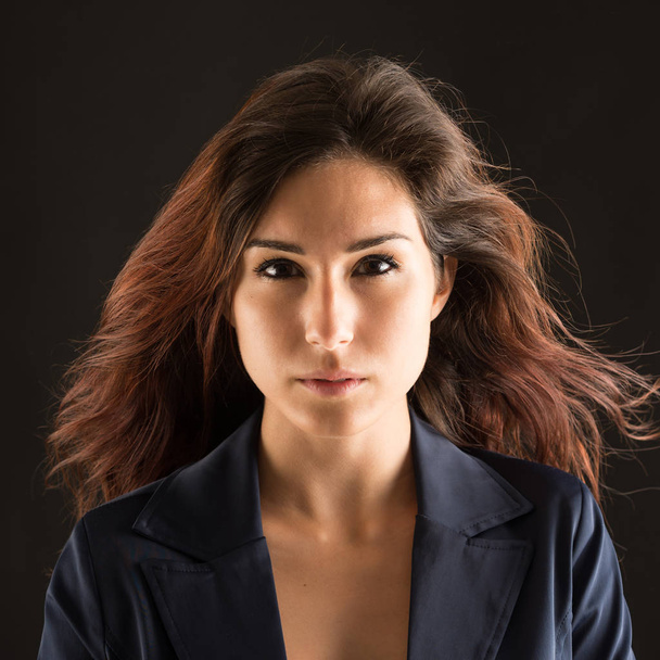 Confident brunette woman studio portrait against dark background - Fotó, kép