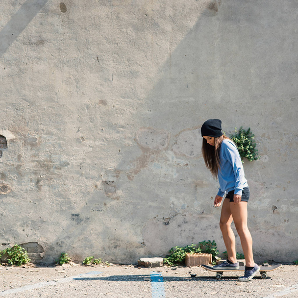 Teenager portrait riding skateboard against concrete wall.  - Фото, изображение