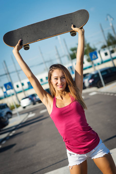 Teenager holding skateboard portrait in the street. - Фото, изображение