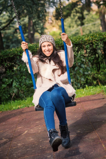 Portait of young woman swinging outdoors in a park in autumn.  - Φωτογραφία, εικόνα