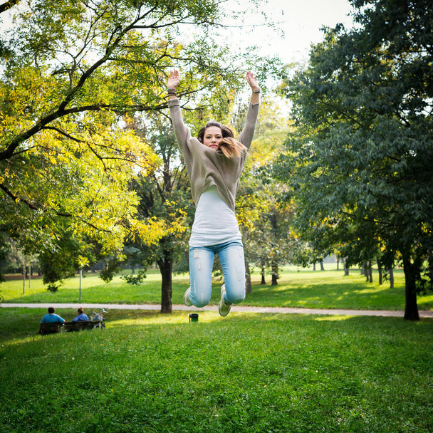 Jumping young woman outdoors in a park. - Foto, Imagen