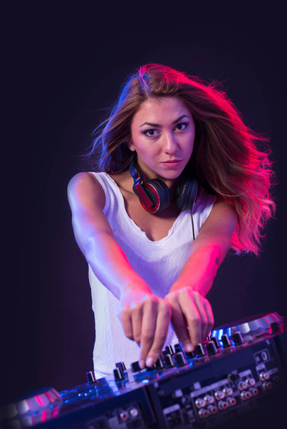Young sexy deejay woman mixing music against black background with strobe light effect.  - Photo, image