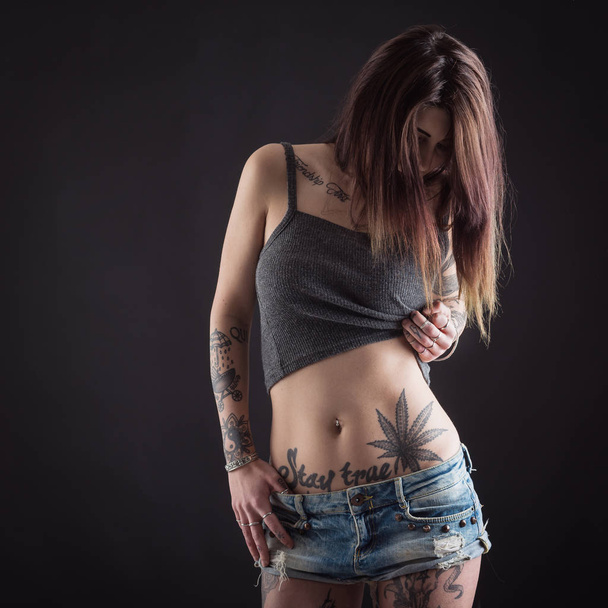 Close up of beautiful woman with tattoo wearing jeans short pain - Zdjęcie, obraz