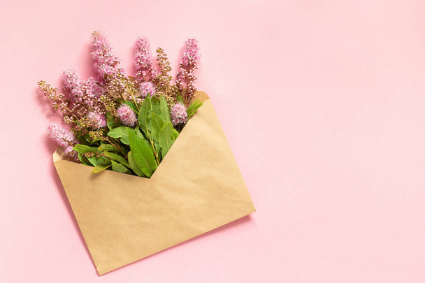 Mező rózsaszín virágok kézműves borítékot rózsaszín háttér üdvözlőlap lakás Lay másolás tér koncepció Hello tavasz - Fotó, kép