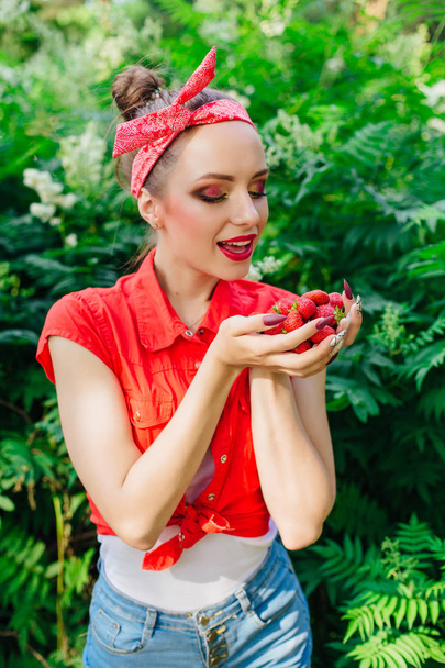 Beautiful young pin up girl with bright make up and fresh natural strawberry. - Foto, Imagen